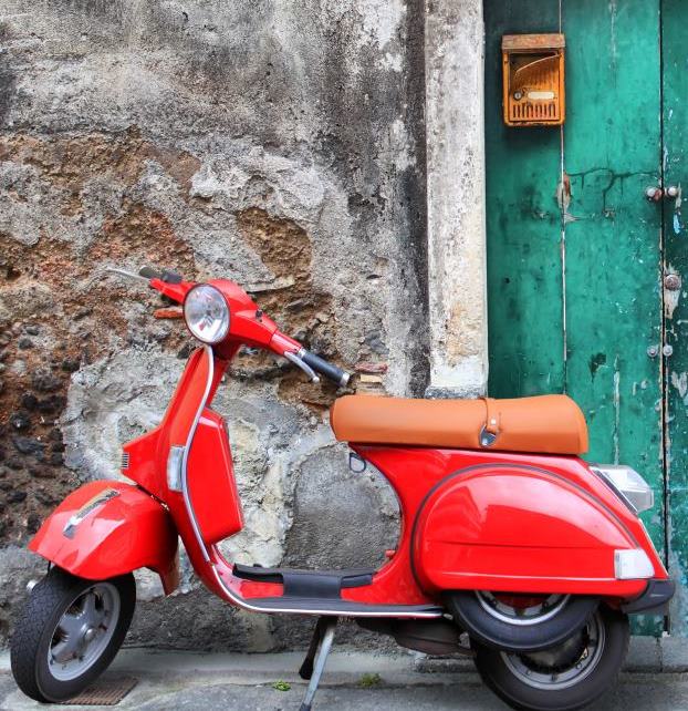 Italia foto de una motocicleta tipo scooter roja y una vivienda vieja de fondo