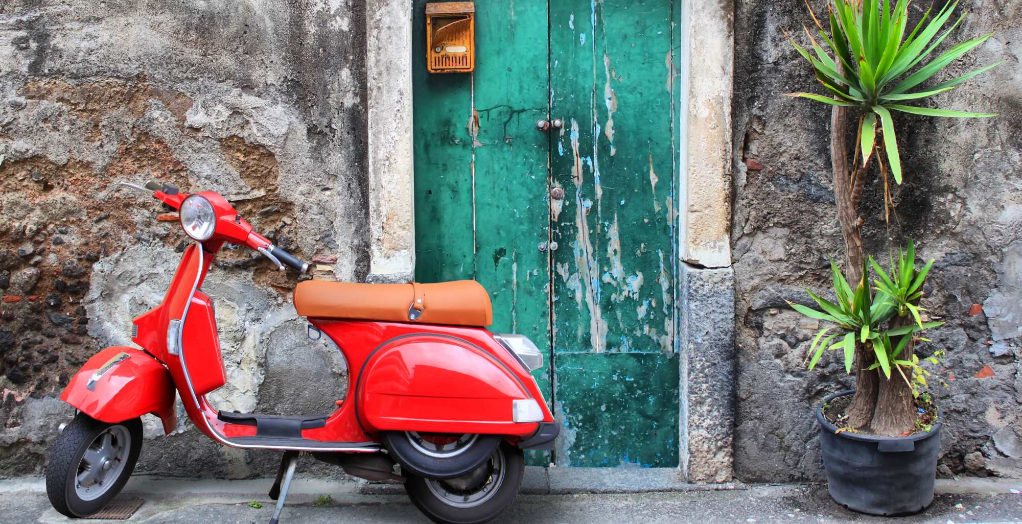 Italia foto de una motocicleta tipo scooter roja y una vivienda vieja de fondo