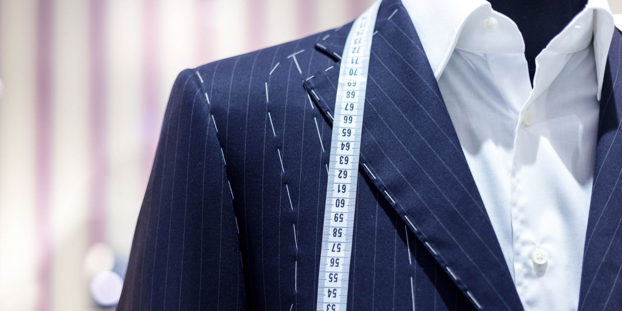 Traje azul con camisa blanca y encima de los hombros una cinta metrica de medición